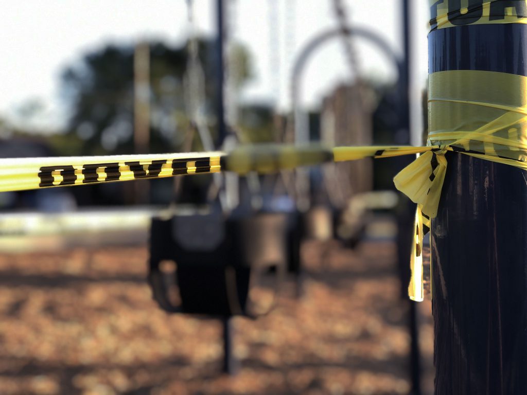 caution tape on a pole in front of a playground