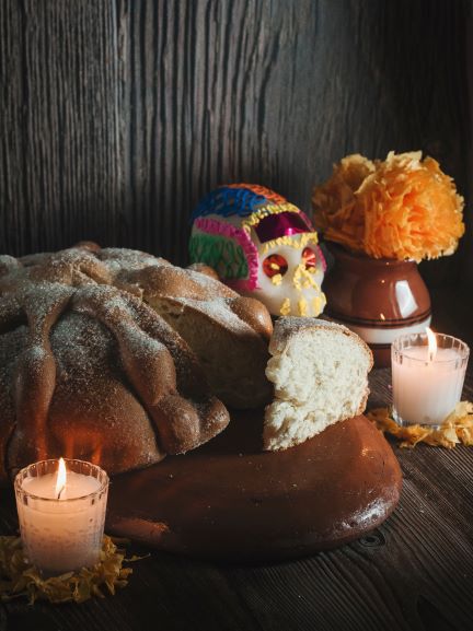Mexican bread of the dead on clay dish with candles and flowers