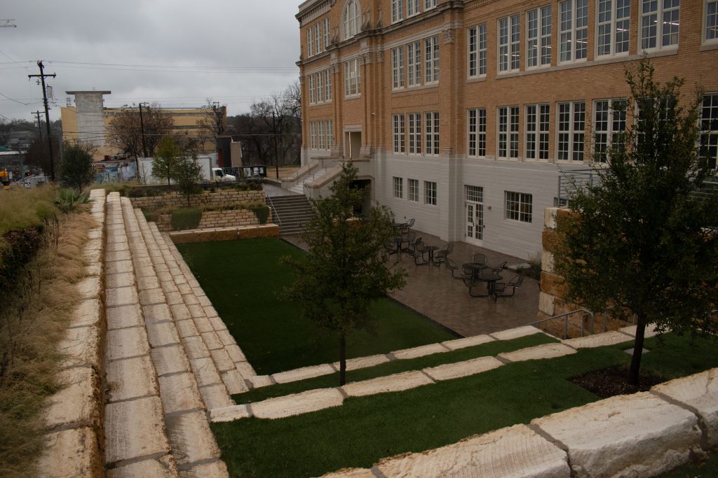 An outdoor image of the side of ACC's Rio Grande campus. There are large steps of limestone that lead into an outdoor lounge area for students.