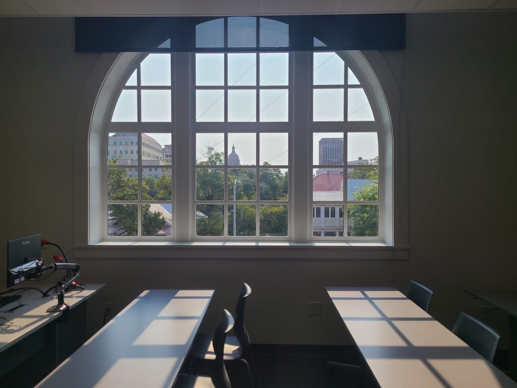 A view from inside an empty classroom at the Rio Grande campus. Through the window you can see a sunny afternoon and the Texas Capitol dome.