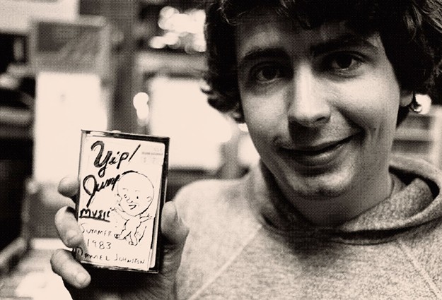 The late Austin artist, Daniel Johnston, smiles with one of his many cassette tapes he would distribute to people near UT.