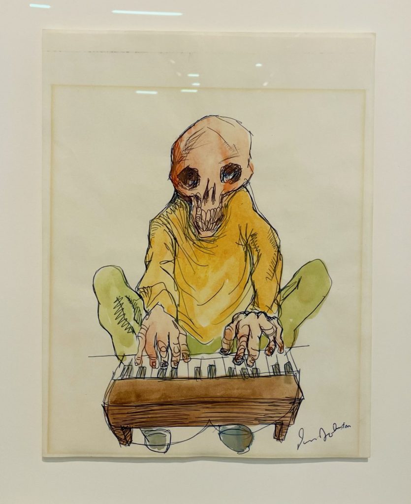 An image of a man with only a skull for a head plays a small piano.
