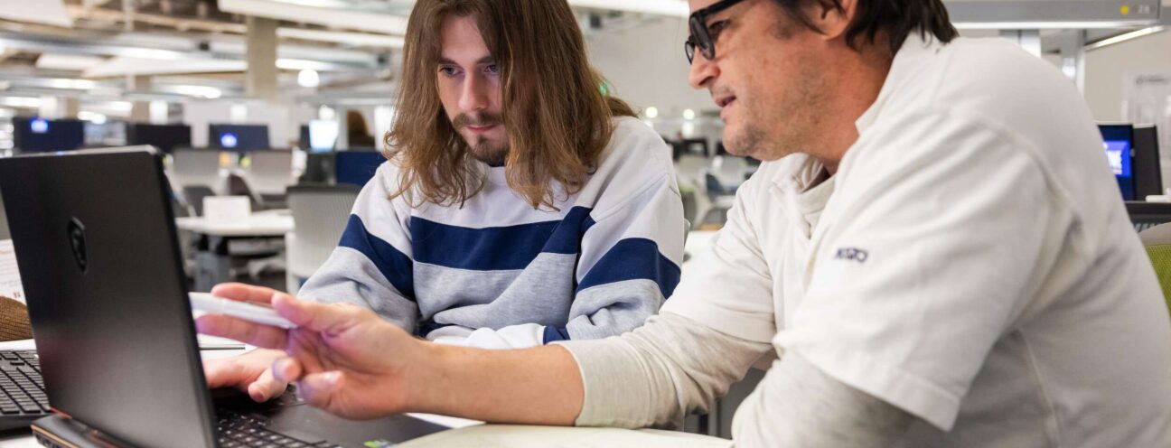 An ACC student and instructor collaborating on a laptop at the ACC Highland ACCelerator focused on their work.