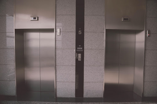 Closed metallic elevator doors in a modern building lobby.