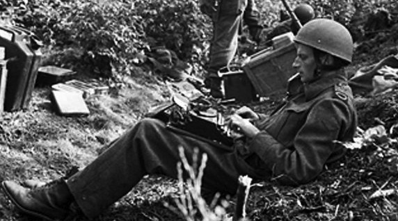 Alan Wood, war correspondent, typing his despatch in a wood outside Arnhem; with him are three members of the 1st British-Airborne Division. 18 September 1944
