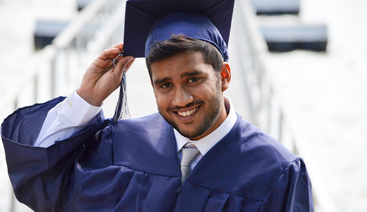 Male college graduate tipping graduation cap
