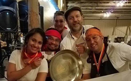 Culinary students who competed in paella competition pose for photo while hold medallions and smiling.