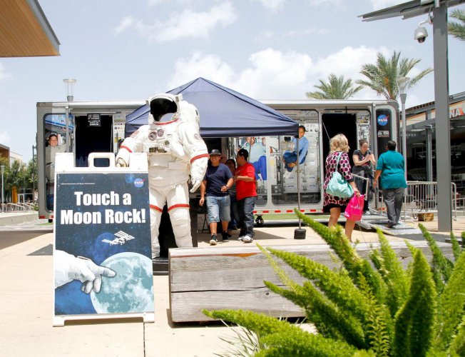 NASA Drive to Explore mobile exhibit van with astronaut suit and Touch a Moon Rock sign in front
