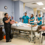 Group of nursing students meet in front of a hospital bed