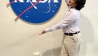 Student participating in NASA Community College Aerospace Scholars (NCAS) program pose for picture in front of NASA sign
