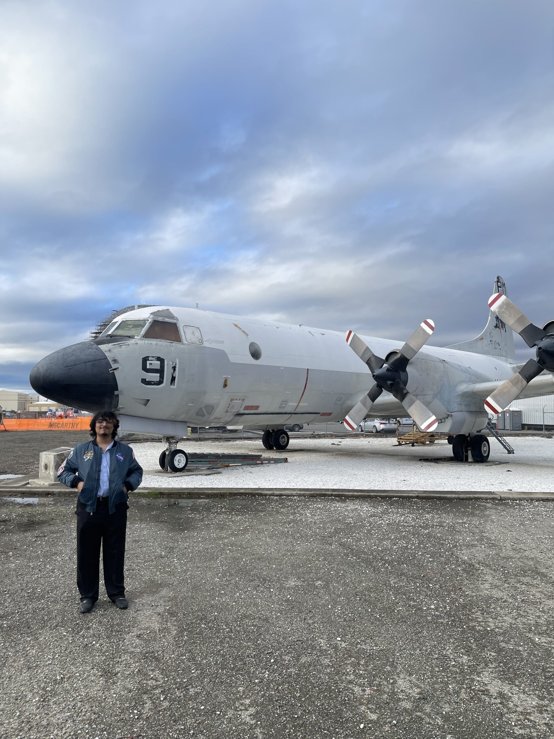 Student participating in NASA Community College Aerospace Scholars (NCAS) program pose for picture in front of airplane