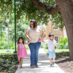 Mother walks down sidewalk with her two children