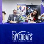 Dr. Russell Lowery-Hart and Amanda Crawford sit at table and sign documents