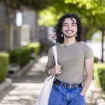 Student smiles at the camera with trees behind him