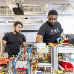 A student and faculty member working behind manufacturing equipment