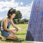 Girl working on a solar panel in a field