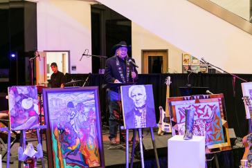 Southwest artist Amado Pena stands with works displayed on easels
