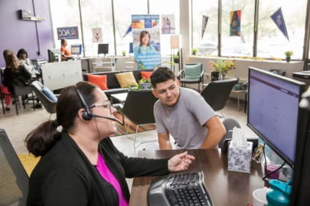 College Destination Center staff member wearing headset views computer screen with male prospective student