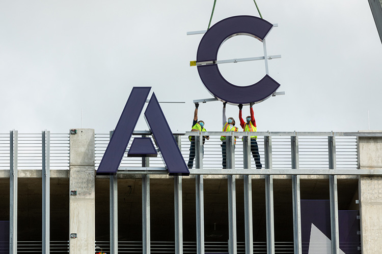 Crews assist with ACC HIGHLAND letters installation on the East facing side of the Highland Campus parking garage, on Wednesday, July 15, 2020.