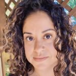 headshot of femal student with brown curly hair looking at the camera.