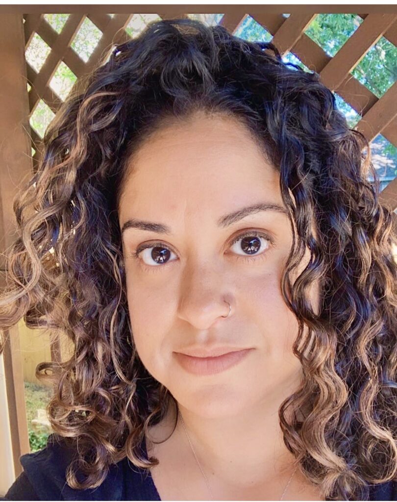 headshot of femal student with brown curly hair looking at the camera. 