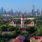 "Aerial view of Main Building at St. Edward's University with the downtown Austin skyline in the background under a clear blue sky."
